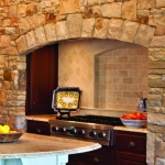 The beautiful kitchen in this Georgia lake house includes a stone hearth designed by Boston Interior Designer Elizabeth Swartz Interiors.