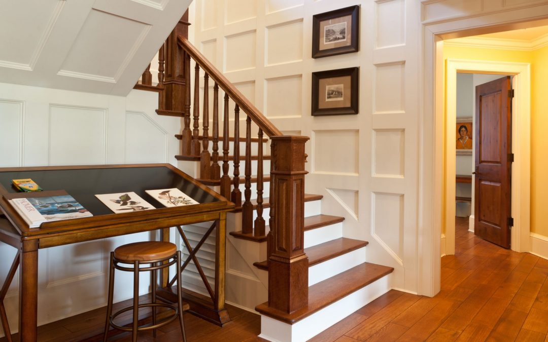 The stairs of this lake house renovation gives a nod to the client's love of traditional decor with custom millwork and wood paneling. Interior design by Boston interior designer Elizabeth Swartz Interiors.