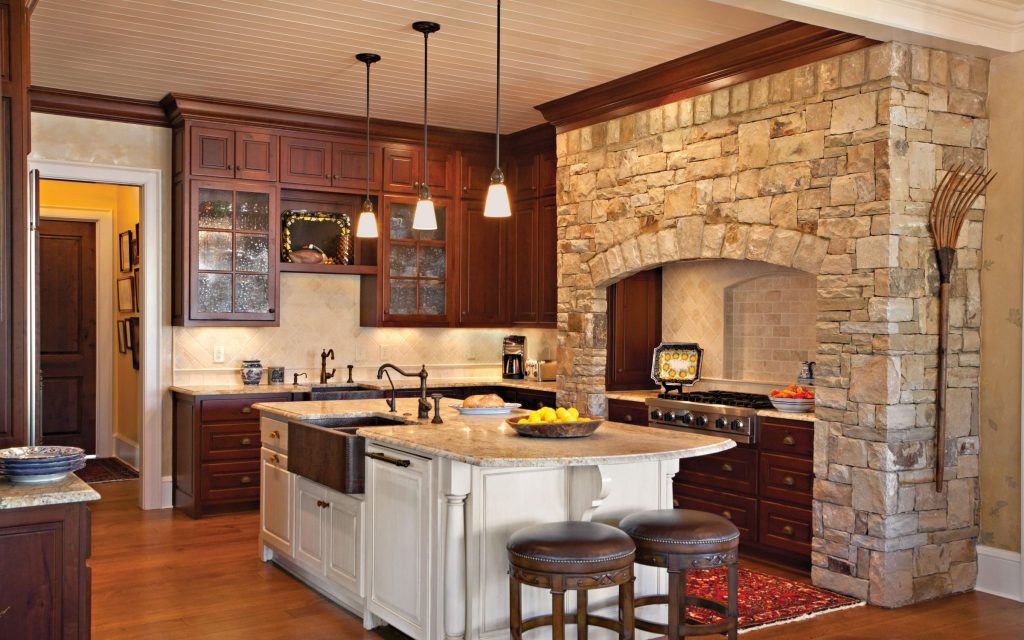 A centrally located large kitchen includes a large island and a stone hearth around the stove in this beautiful kitchen designed by Boston Interior Designer Elizabeth Swartz Interiors.