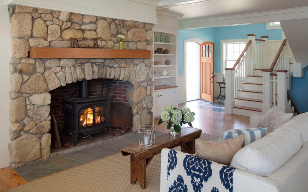 The interior design of the living room in this beach cottage on Martha's Vineyard by Boston Interior Designer Elizabeth Swartz Interiors features cool blues, warm woods and a fieldstone fireplace, reflecting the home's island roots.