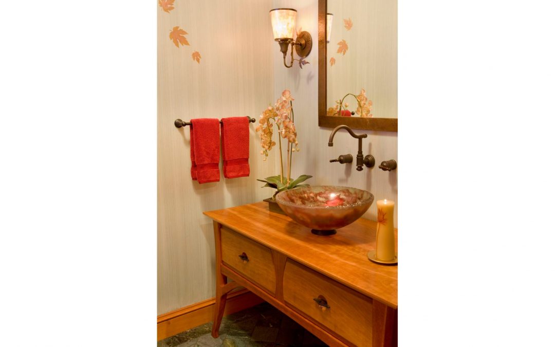 The powder room of this White Mountain retreat designed by Boston Interior Designer Elizabeth Swartz Interiors utilizes warm woods and custom wallpaper with a modern outdoor motif to bring the outside in.