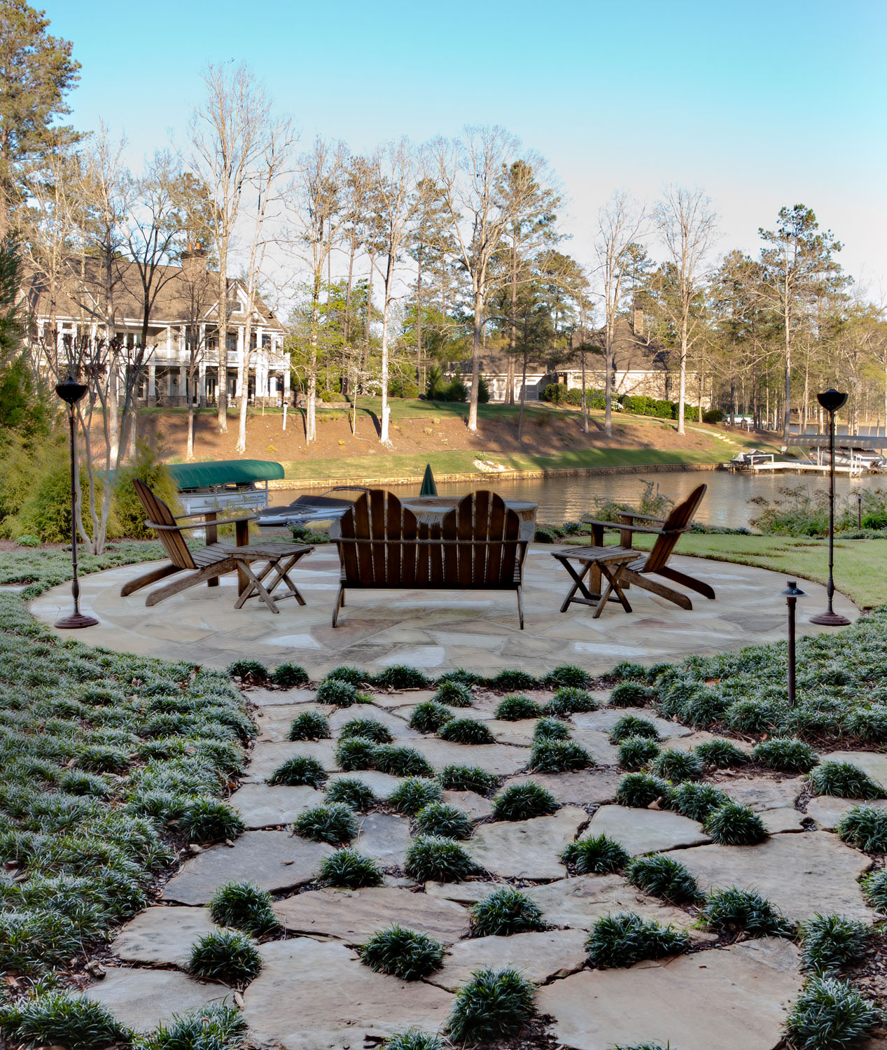 A lakeside patio with tiki torches adds a warm ambiance to living outdoors.