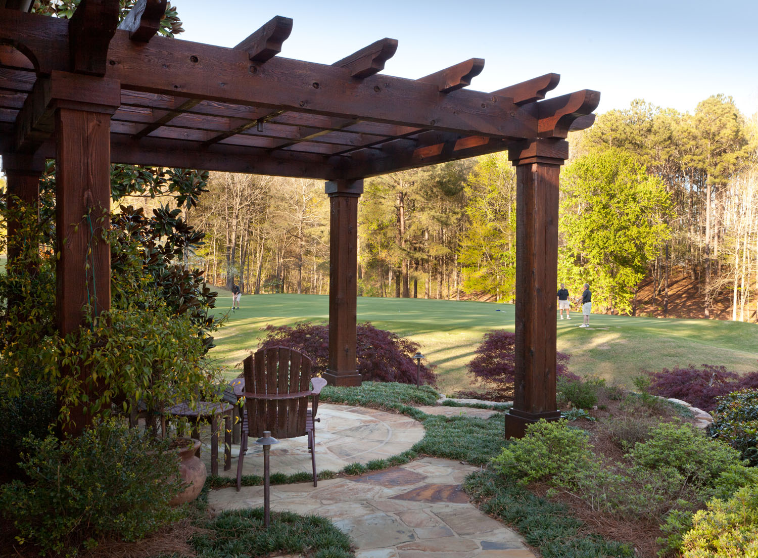 Living outdoors at this lakeside home designed by Boston Interior Designer Elizabeth Swartz Interiors includes a pergola overlooking the golf course.