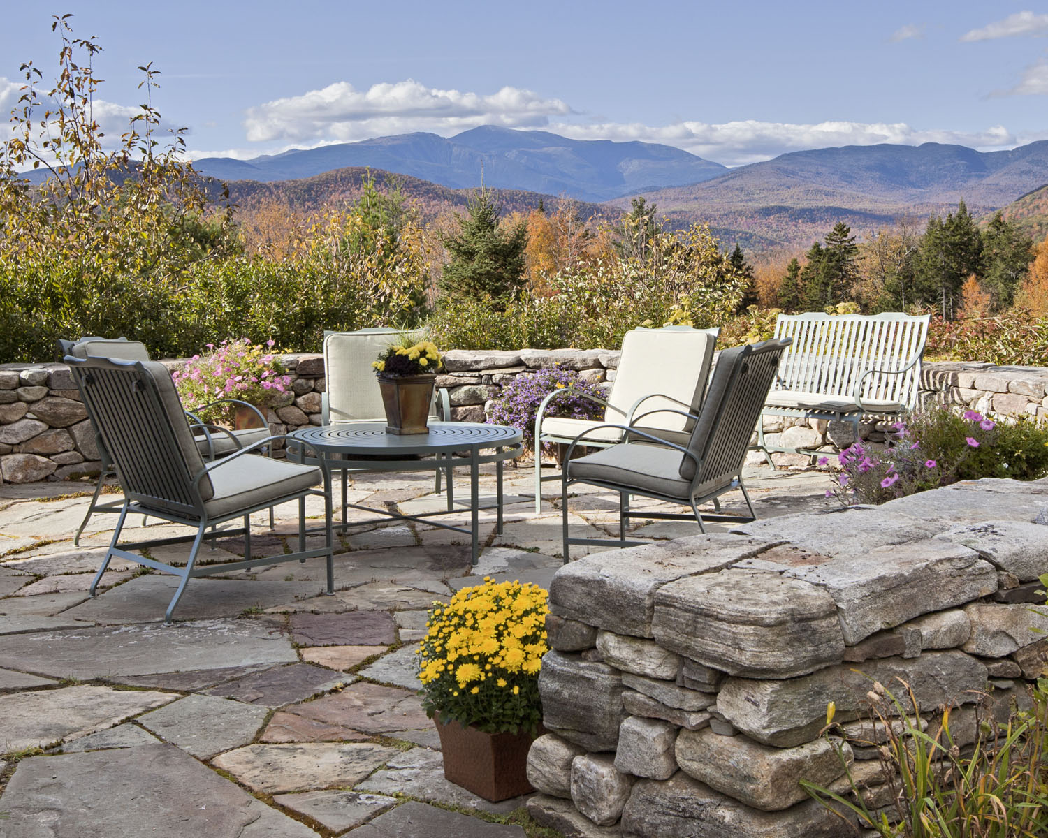 This space designed for living outdoors in the White Mountains was designed by Boston interior designer Elizabeth Swartz Interiors utilizing a short stone wall to define the space.